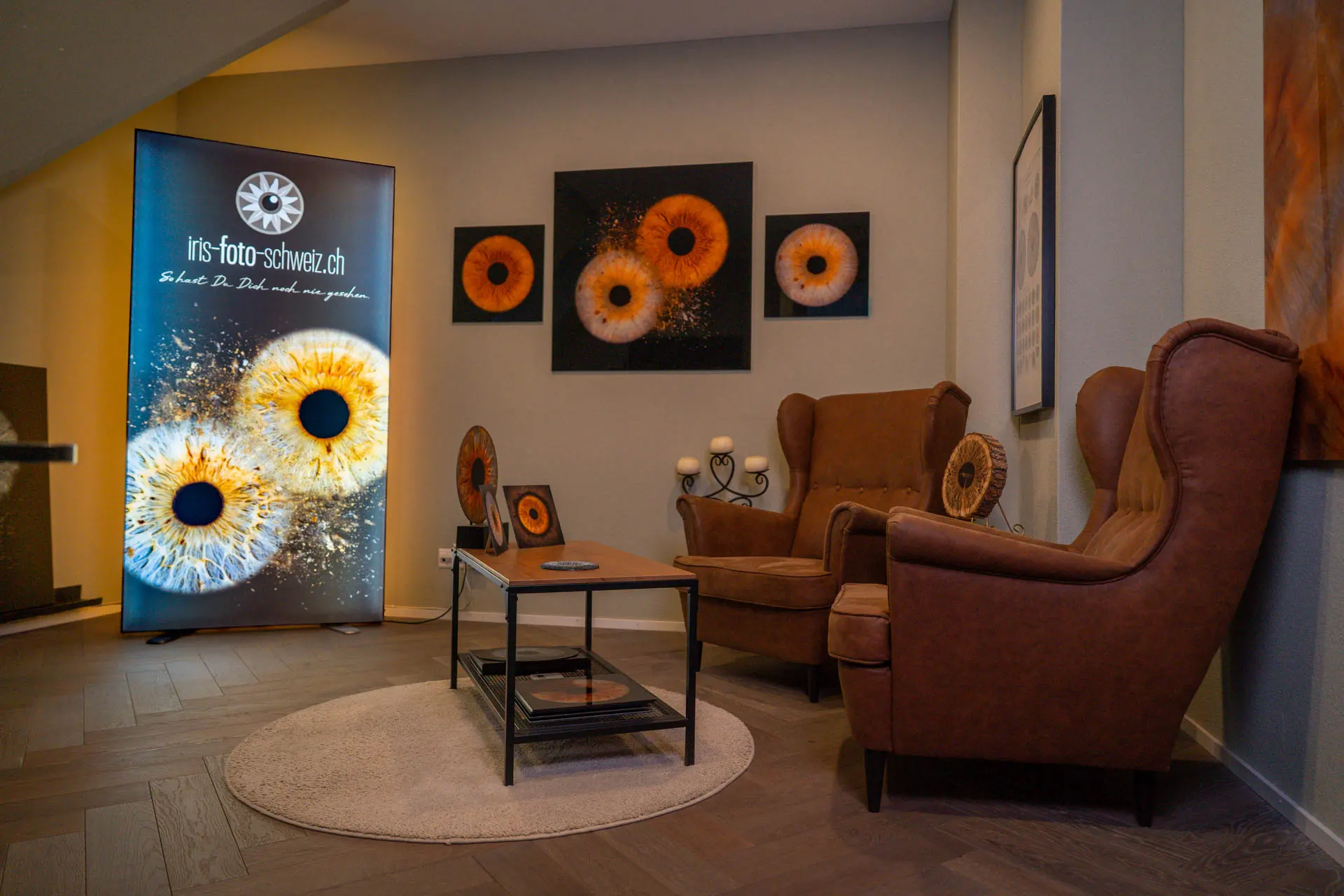 Iris Foto Studio Luzern – Lounge mit Iris Wandbildern, Leuchtdisplay und Ledersesseln